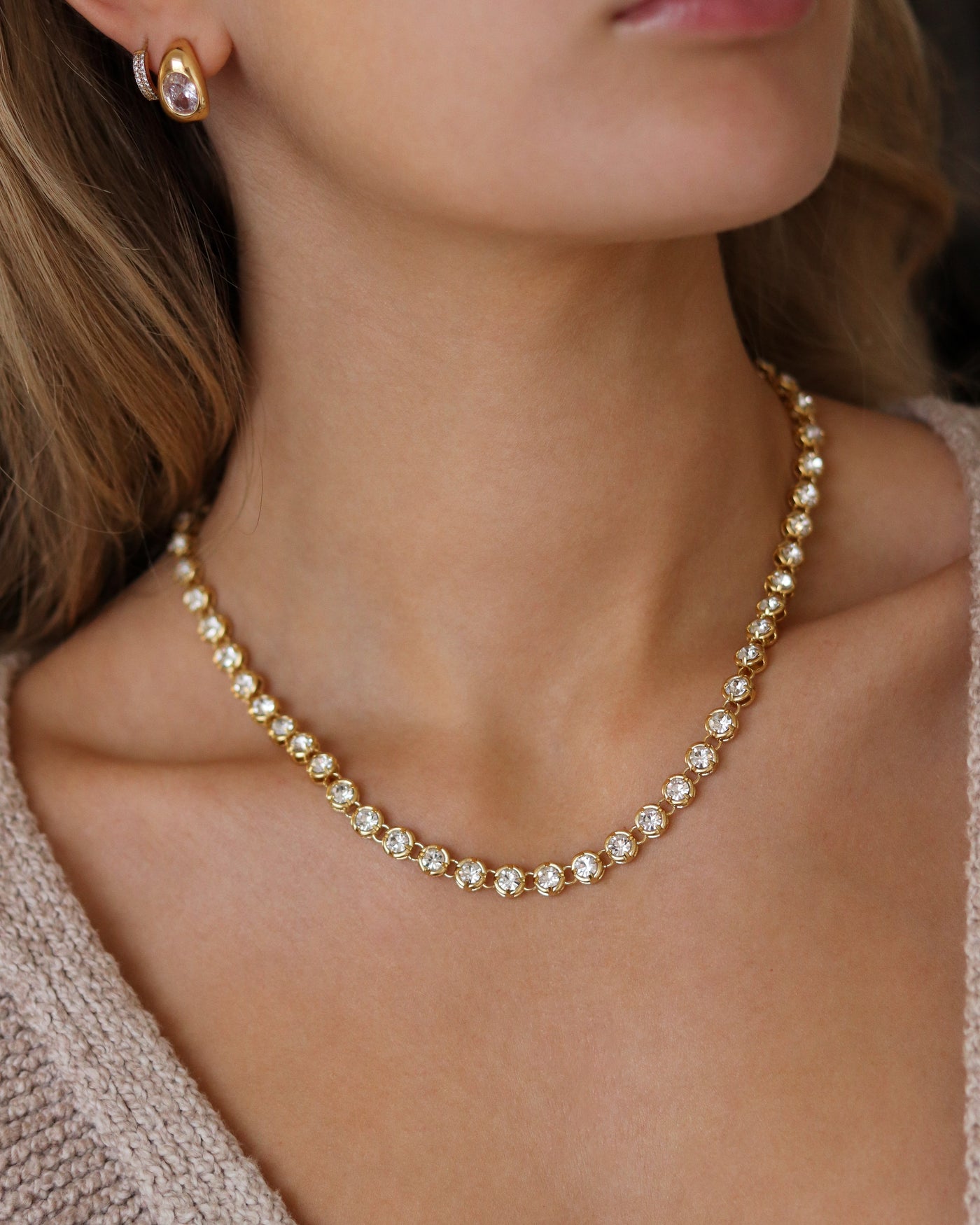 Close-up of a woman wearing a crystal bezel necklace and earrings.