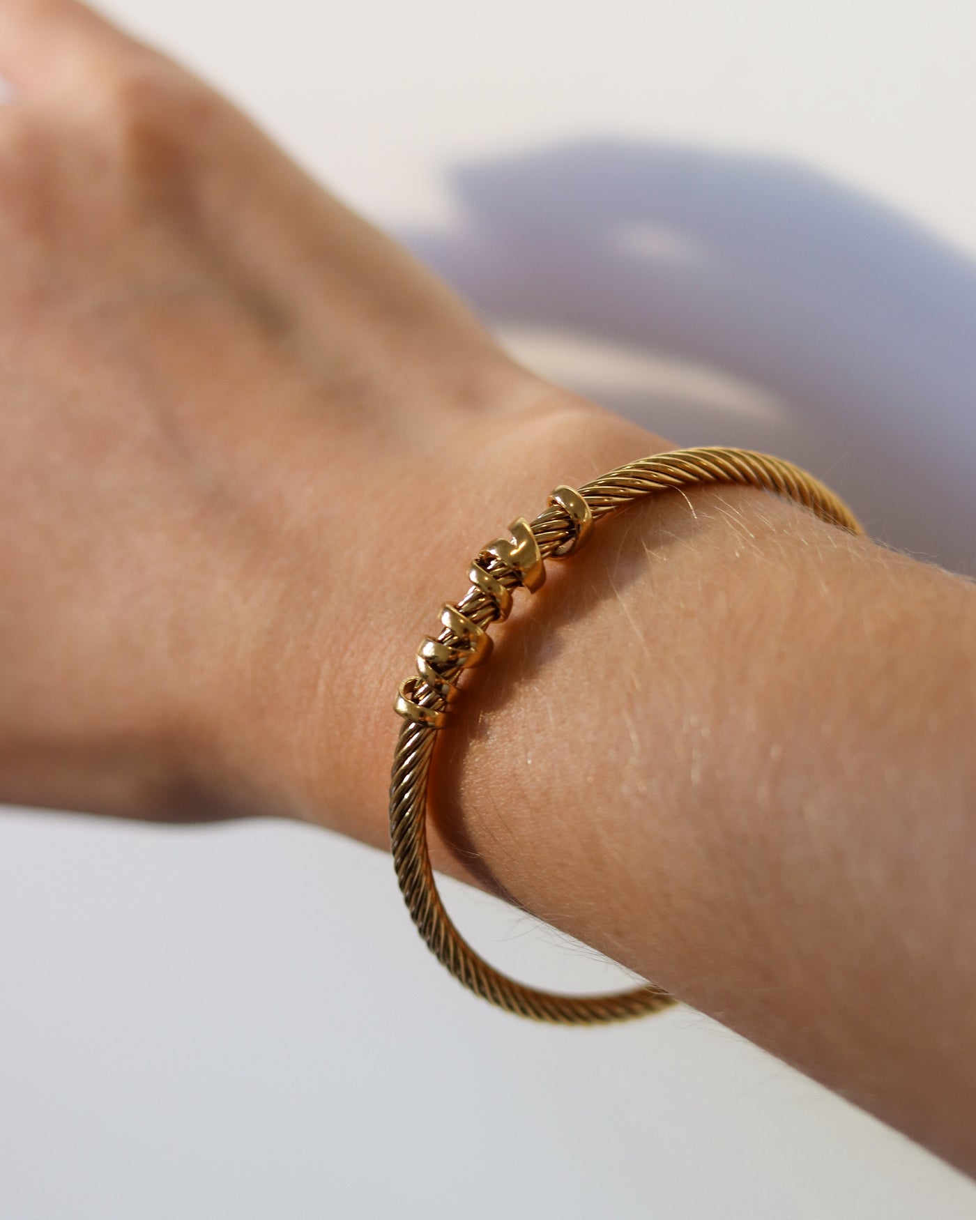 Gold bracelet on a wrist with a blurred background
